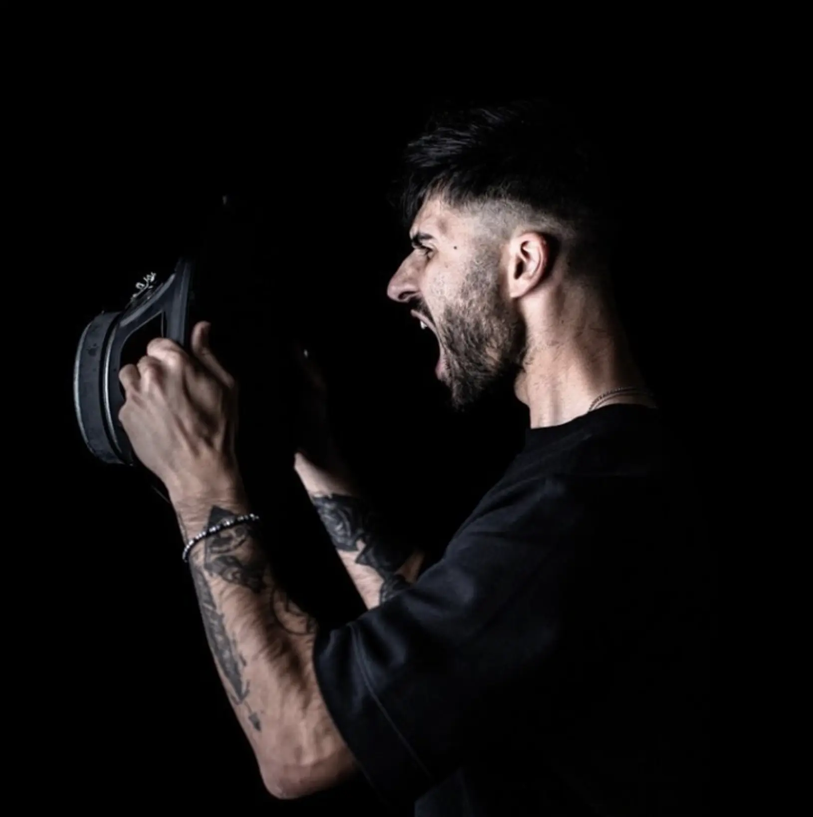 CEKA di profilo che urla tenendo le cuffie in mano
